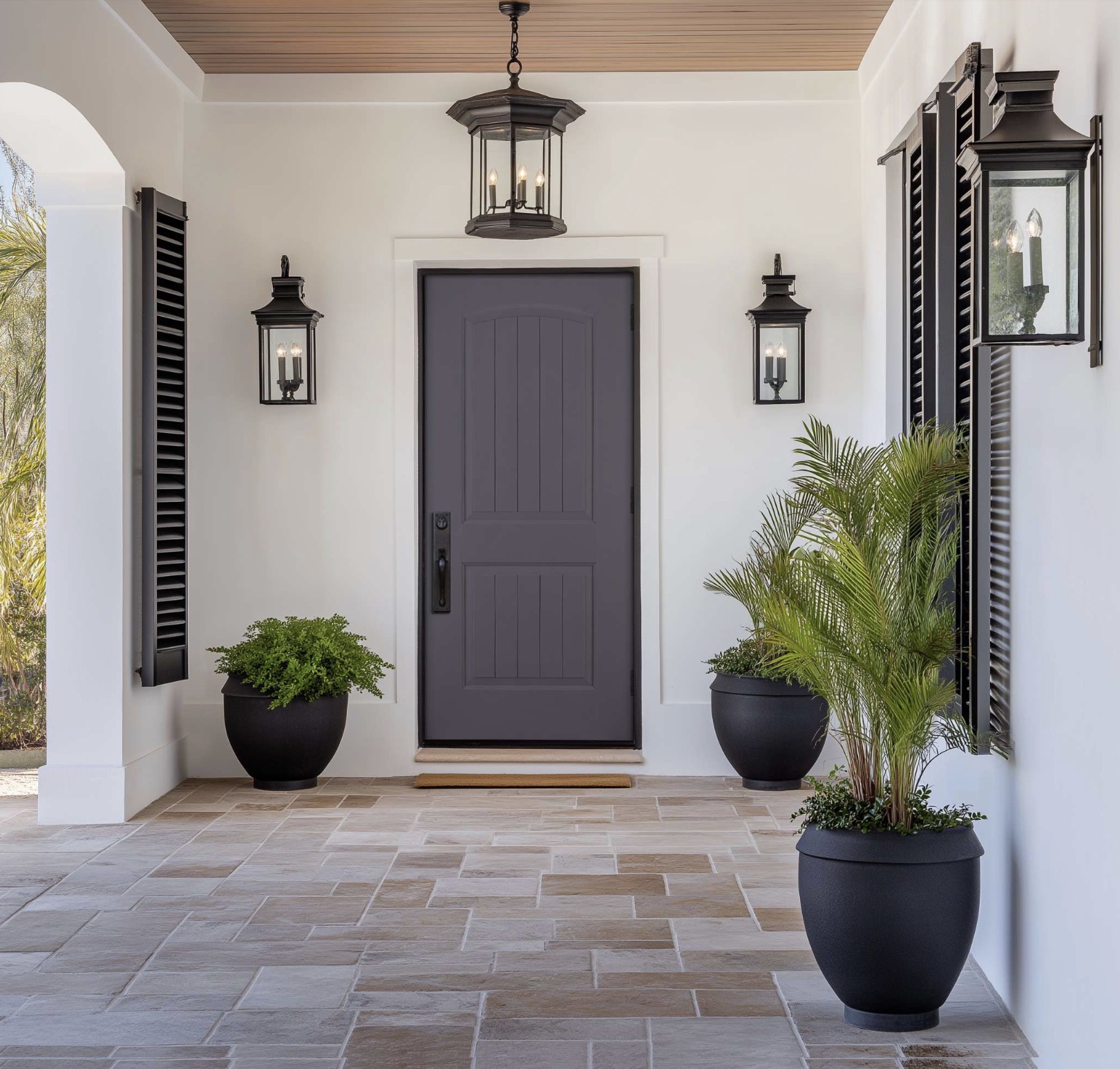 Dark entry door with coordinated exterior lighting and planters