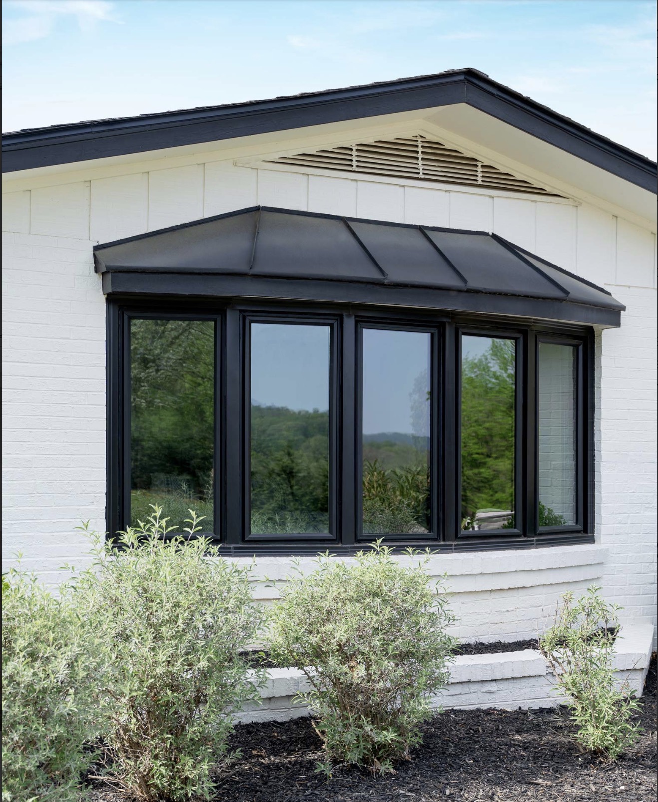 Black bay window on a white brick home